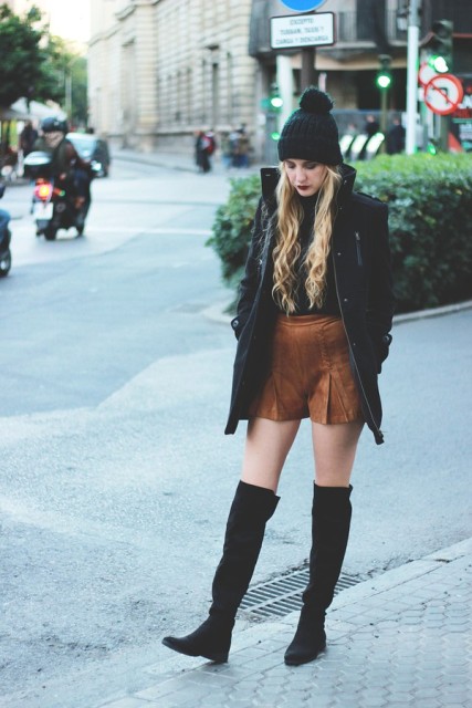 With green pom pom hat, black coat and over the knee boots