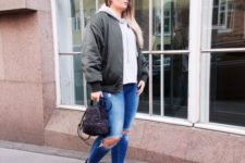 With light gray hoodie, distressed jeans, black and white sneakers and gray bomber jacket