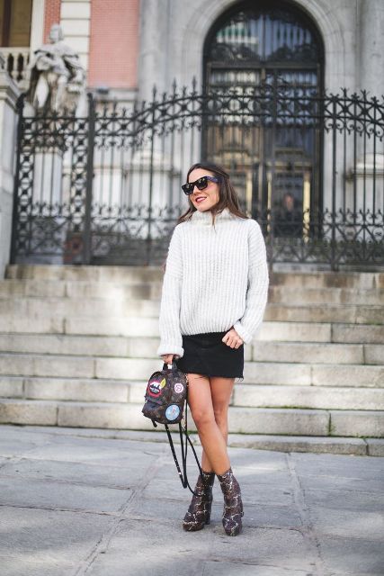 With loose sweater, black mini skirt and printed ankle boots