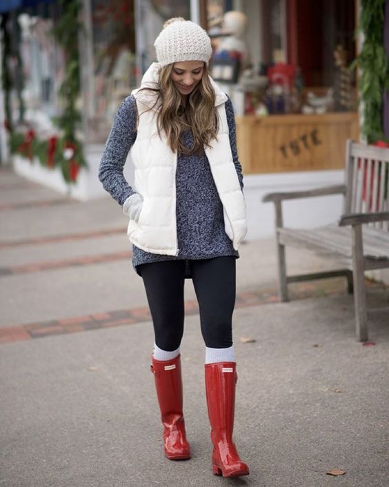 a grey sweater, black leggings, white leg warmers, red rubber boots, a white puffer vest and a white beanie