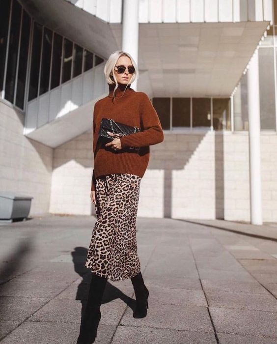a leopard midi skirt, a rust turtleneck sweater, black boots and a black clutch to enjoy colors