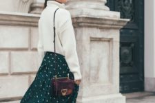 a white oversized sweater, a green polka dot midi skirt, plum-colored boots and a matching bag
