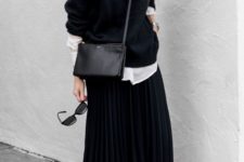 a white shirt, a black sweater over it, a black pleated midi skirt, white sneakers and a black bag