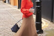 compose a bright winter outfit of a beige midi skirt, a coral sweater, black boots and a black bag