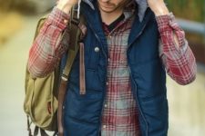02 a dynamic winter outfit with green pants, a black tee, a plaid shirt, a navy waistcoat with a hood and backpack