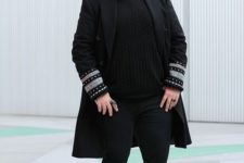 03 a total black look with jeans, boots, a sweater and a coat with printed sleeves is super chic