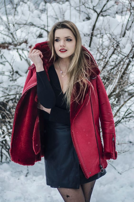 a black top with a V-neckline, a black leather skirt and a deep red shearlign coat for a colorful touch