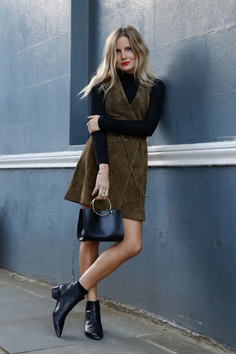 A black turtleneck, a brown suede dress, a black bag and black booties to rock