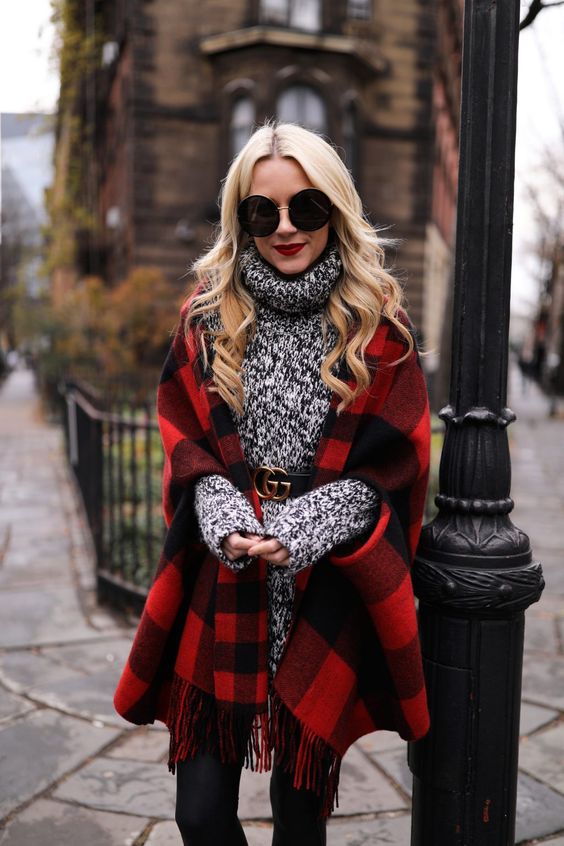 black skinnies, a long sweater with a logo belt and a plaid cape as a trendy touch to the outfit