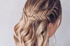 a boho half updo on medium hair, with a large fishtail braid on one side and waves down is a stylish solution