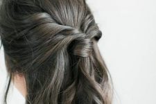 a boho half updo with a sleek top, a twisted ponytail and waves down is a lovely solution