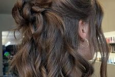 a classy half updo with a halo, a messy top knot and waves down plus locks framing the face
