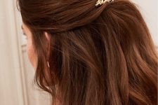 a fantastic half updo with a twisted low ponytail and some volumetric wavy hair with a catchy hairpin is a chic solution