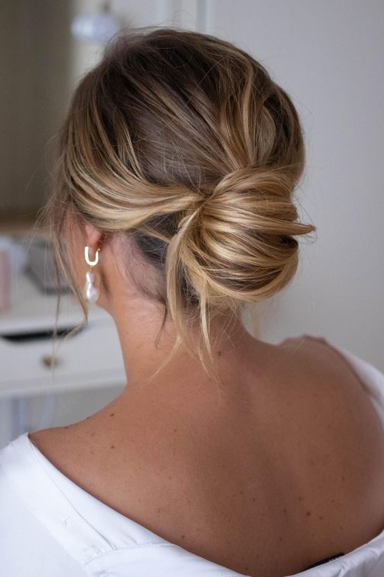 a messy chignon with a messy top and waves down is a chic modern solution for the holidays