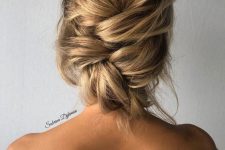 a messy woven low updo with a bump on top and some locks down is a chic and cool idea for the holidays