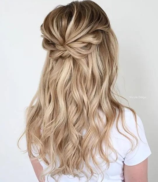 a pretty boho half updo with a dimensional bump, a loose braided halo and waves down is a cool idea for a romantic party look