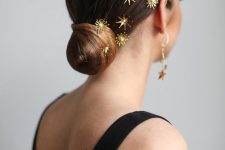 a very sleek and chic low bun with a sleek top and gold star hair pins is amazing for a refined holiday look