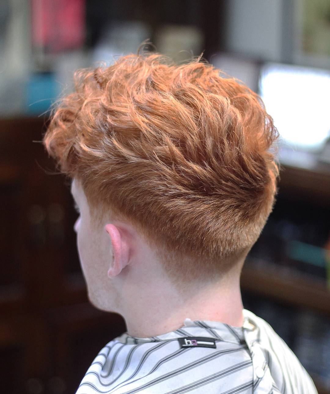 A medium length curly haircut and a low fade is a bold modern option