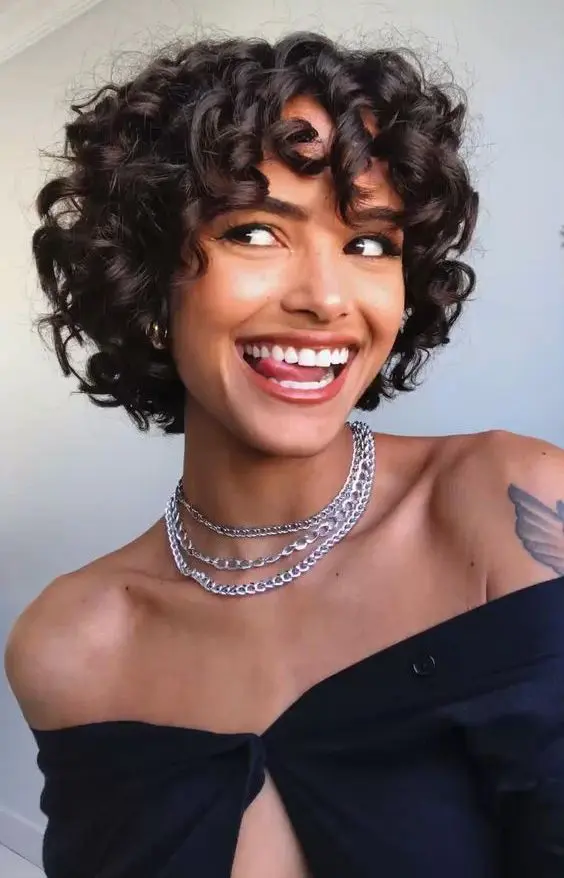 a black chin-length curly bob to pixie haircut with bangs is a lovely and chic idea to rock if you have curls