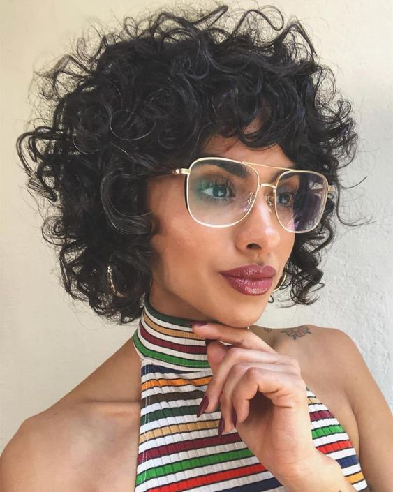 a chin-length curly black bob haircut with bangs is a supr cool and bold idea to try right now