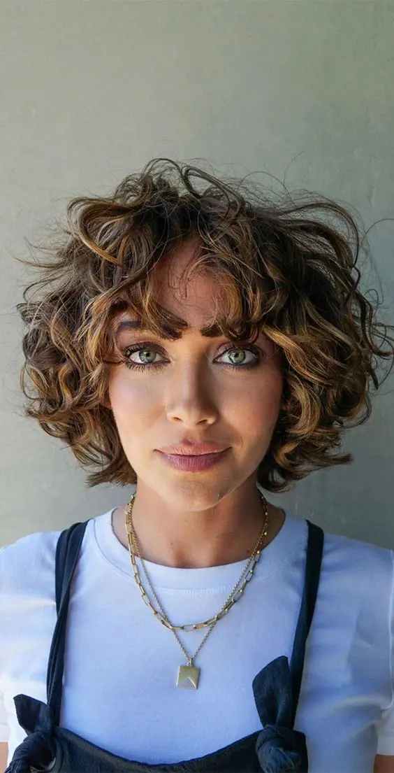 a lovely chin-length curly bob in dark brunette and with caramel balayage, with a lot of volume is wow