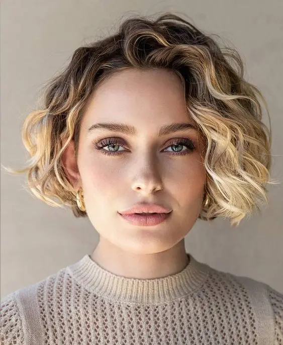a short curly bob with blonde balayage and darker roots is a cool and chic solution to rock right now