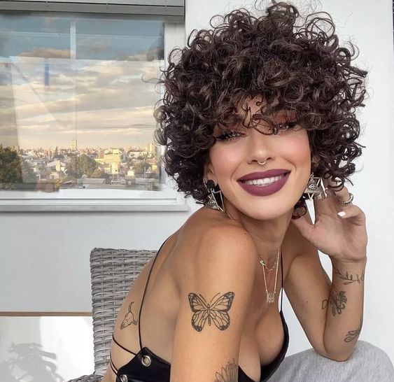 a super short brunette curly bob with a lot of volume is a very cool and bold idea to rock