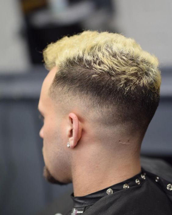 a fade haircut with short spiky hair and blonde highlights on top for a statement