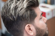 low taper fade and thick textured brush back is stylishly accented with blonde streaks