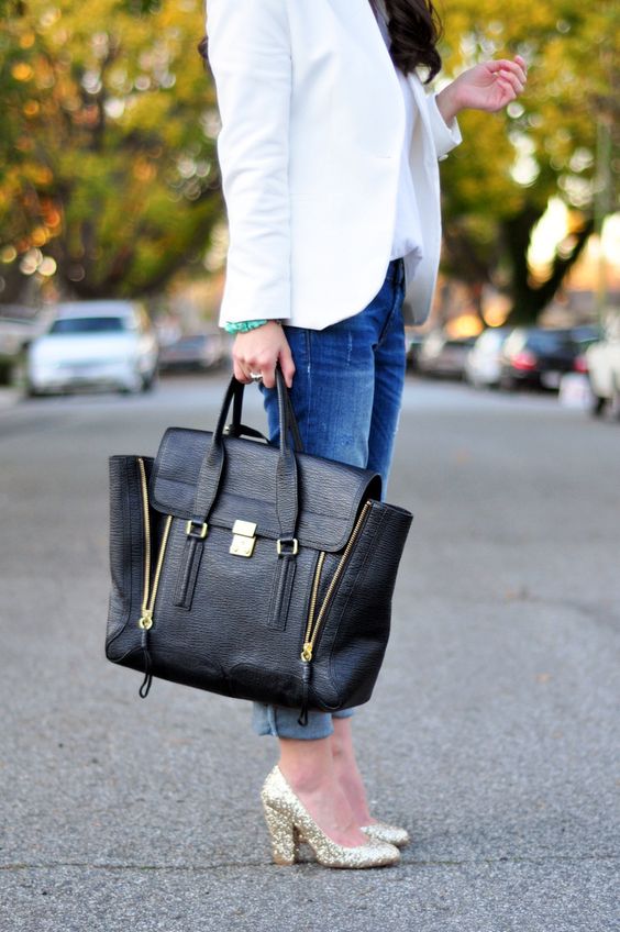 a white shirt, a white blazer, blue jeans, glitter heels and a black bag with zips