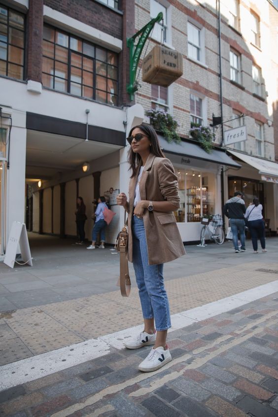 a casual outfit with cropped jeans, a white tee, white sneakers, a camel blazer and a bag