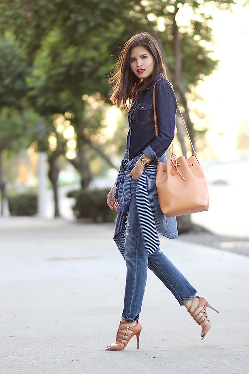 a navy denim ahcmbray shirt, blue jeans, strappy heels and a tan bucket bag