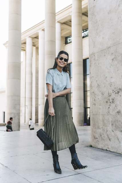 With light blue button down shirt, olive green pleated skirt and embellished bag