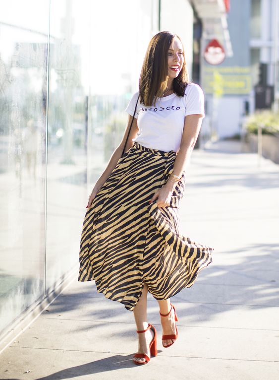 a graphic tee, a zebra print midi skirt, red shoes and a small bag