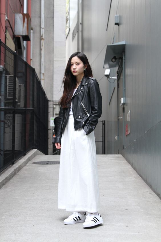 a white top, a white maxi skirt with pockets, white sneakers and an oversized leather jacket