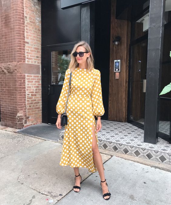 a mustard polka dot midi dress with catchy sleeves and a side slit, black shoes and a bag