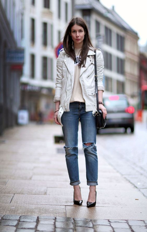 a neutral printed tee, a white leather jacket, blue ripped jeans and black shoes