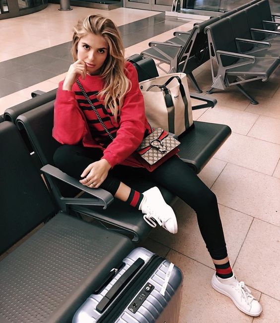 black leggings, striped socks, white sneakers, a red hoodie and a crossbody with a red touch