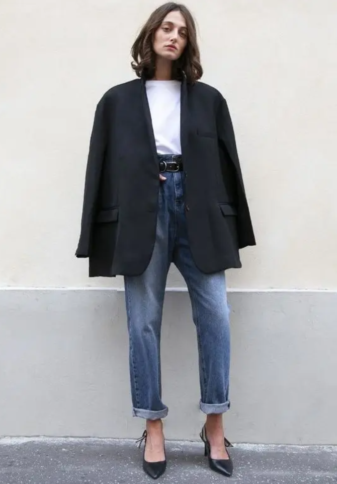 A white t shirt, blue cuffed jeans, black slingbacks, an oversized black blazer compose a stylish work outfit or an everyday one