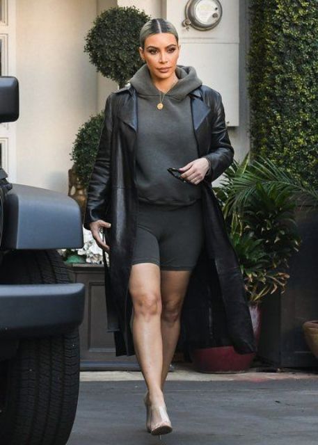 grey bike shorts and a matching hoodie, heels and a black leather trench by Kim Kardashian