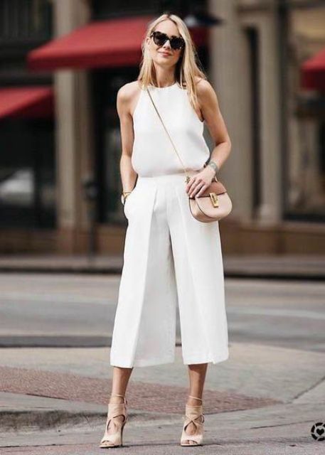 a total white look with a halter neckline top, culottes, a tan bag and nude shoes