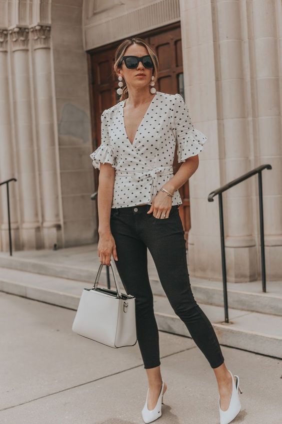 black skinnies, a black and white polka dot tie shirt with ruffled sleeves, white heels and a white bag