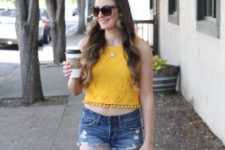 With distressed denim shorts, sunglasses and brown clutch