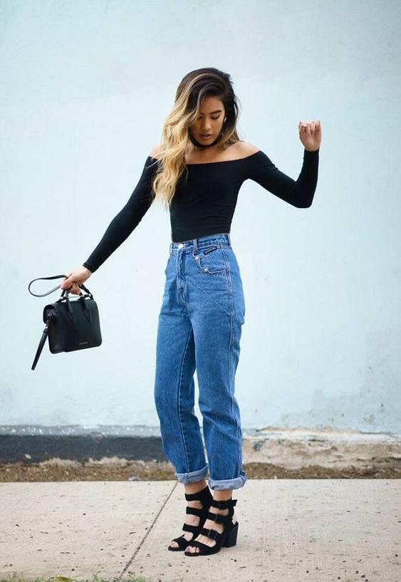 a black off the shoulder top, blue mom jeans, black strappy shoes and a black bag