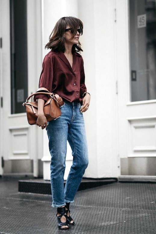 a burgundy silk button down, blue jeans, black strappy shoes and a brown bag