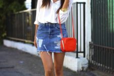 a deconstructed blue denim mini, a white button down, white sneakers and a small red bag for an accent