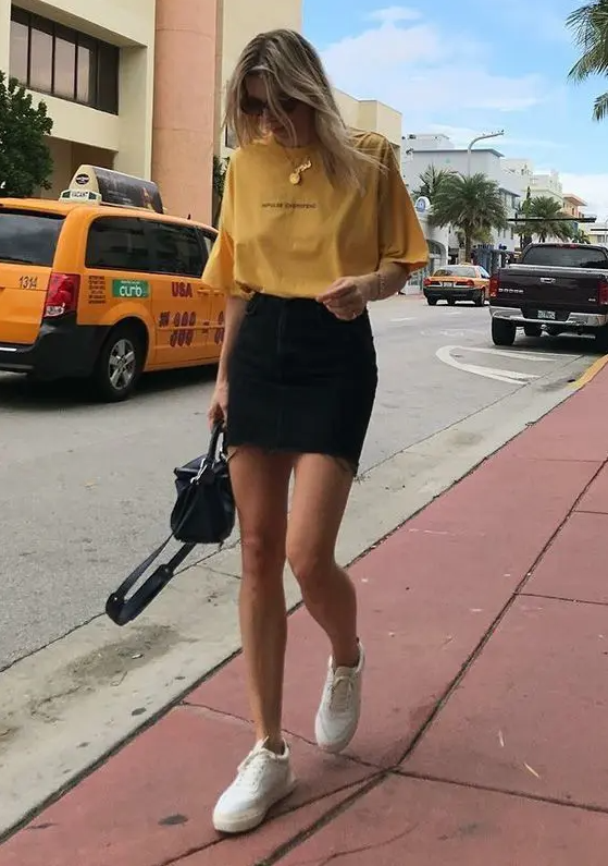 A lovely and easy summer look with a yellow t shirt, a black denim mini, white sneakers and a black bag is easy to repeat