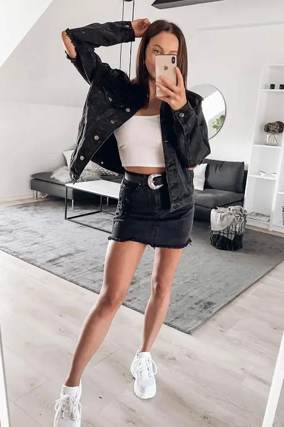 a simple double denim look with a white crop top, a black denim jacket and mini skirt, white trainers