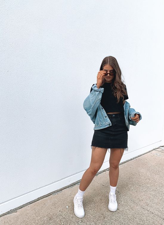 a spring outfit with a black tee, a black denim mini, a blue denim jacket, white sneakers and socks