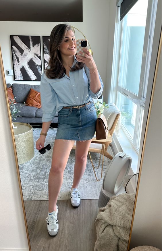 a spring outfit with a blue button down, a blue denim mini, white sneakers and a brown bag and a belt